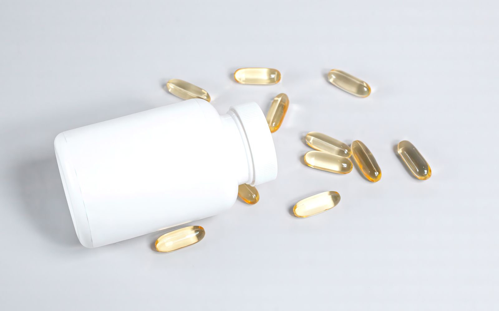 Softgel capsules beside an open supplement bottle