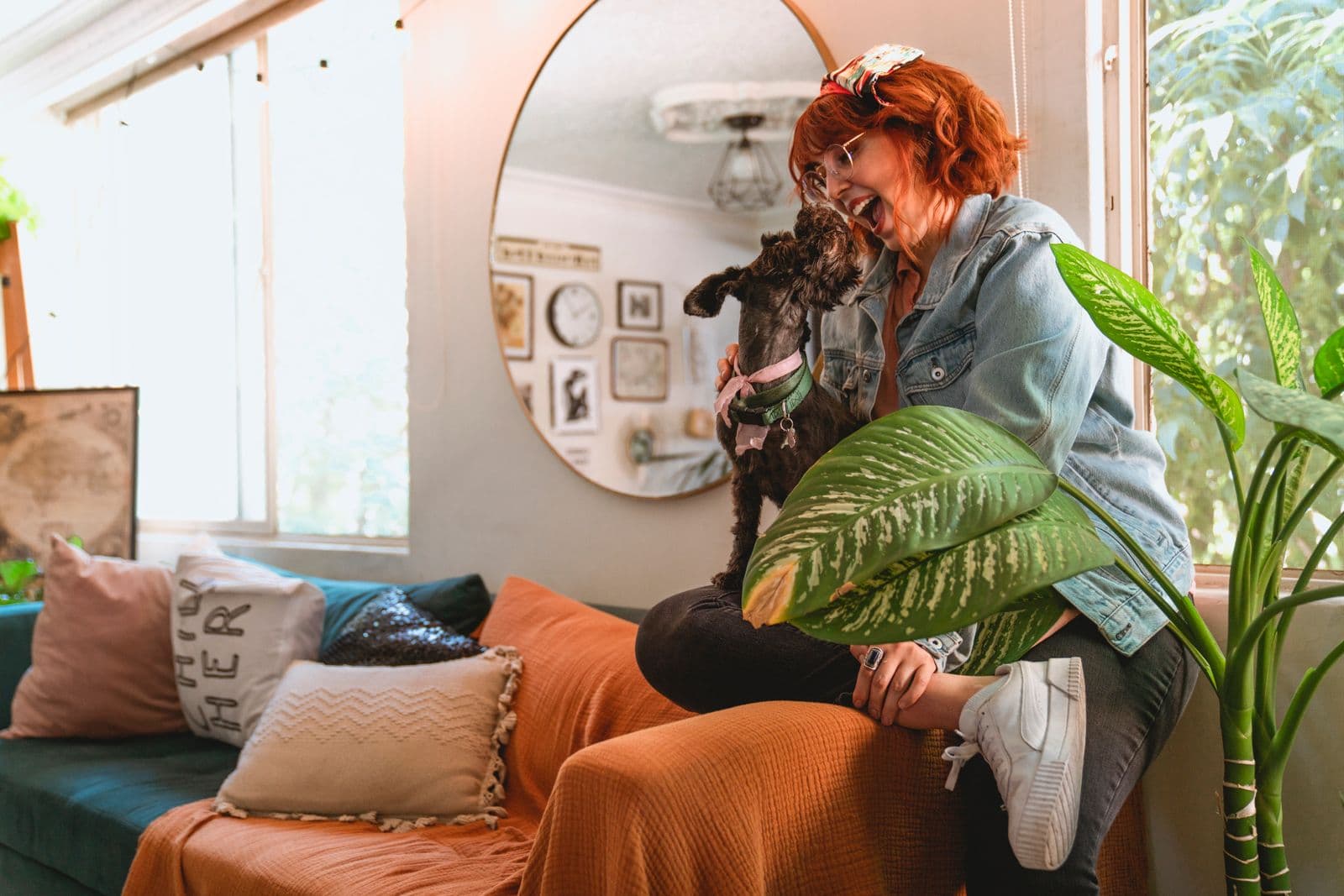 A woman sitting on a couch holding her small dog